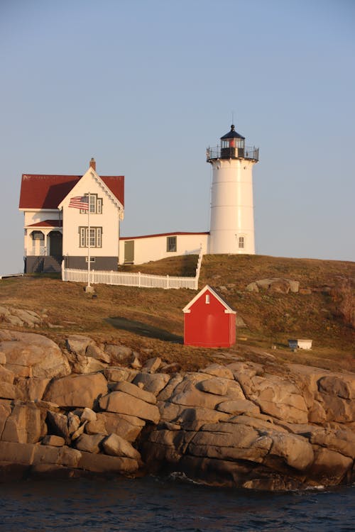 Lighthouse on beside White Wooden Cabin 