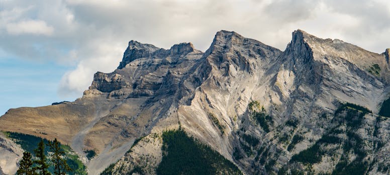 Panoramic view of a rocky mountain peak under a cloudy sky, showcasing nature's grandeur.