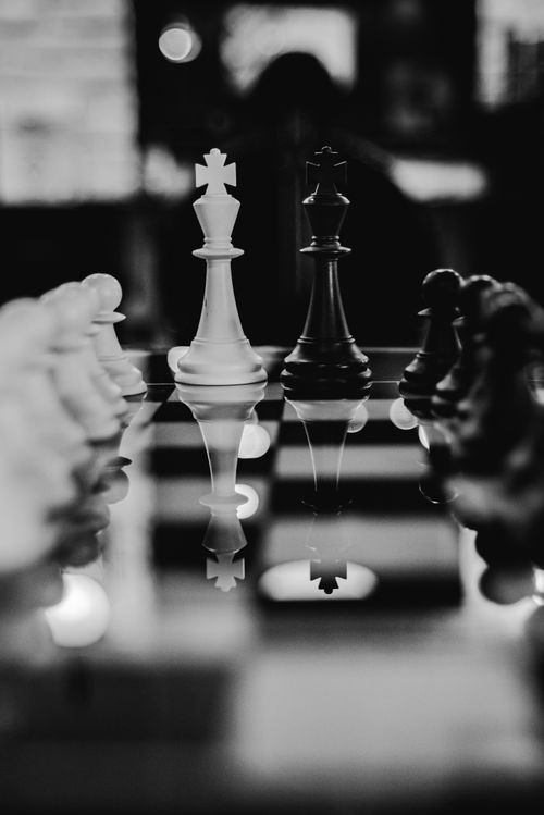 Free An artistic black and white photo of a chessboard with reflective pieces, emphasizing strategy. Stock Photo