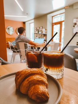 A welcoming cafe setting with a croissant and iced drinks, perfect for a relaxing afternoon.