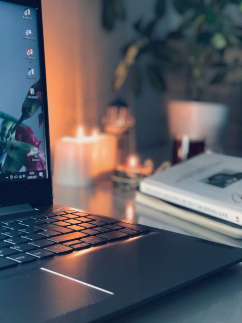 Free A warm and inviting workspace with a laptop, candles, and plants, ideal for productivity. Stock Photo