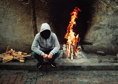 Person Sitting near Bonfire by Wall