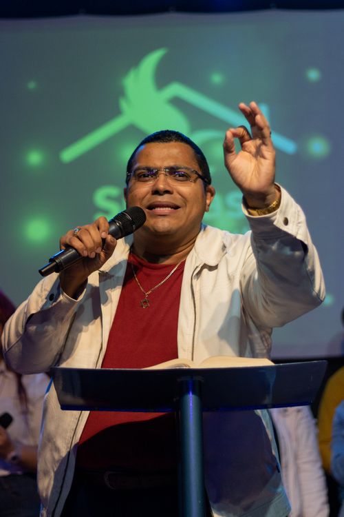 Free Man passionately delivering a speech with microphone at indoor event. Stock Photo