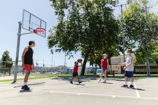 A group of teenagers playing basketball outdoors on a sunny day.