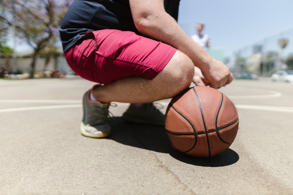 Close-up of a basketball player holding a ball on an outdoor court.