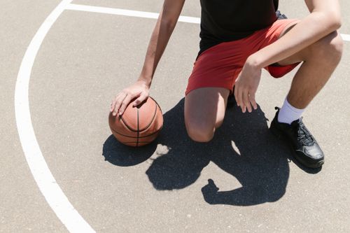 Free A young athlete kneels on an outdoor basketball court ready to play. Stock Photo