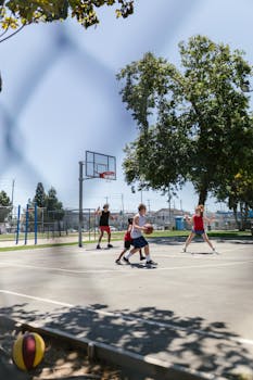 Three young adults playing basketball outdoors on a sunny day.