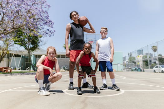 Energetic youth basketball team posing confidently under clear skies on an outdoor court.
