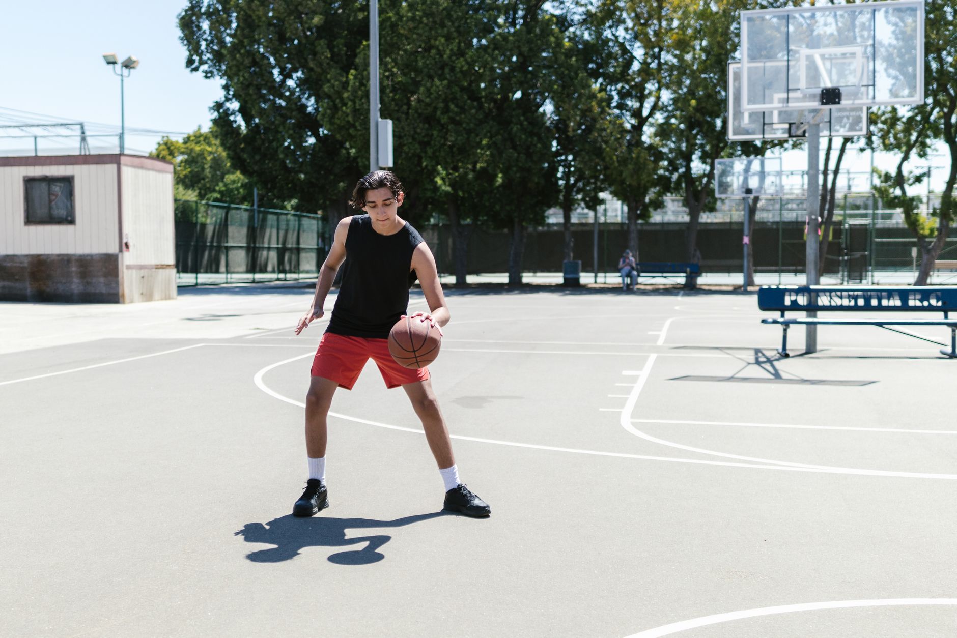 young basketball player practicing low crossovers on an outdoor court at sunrise, focused and determined