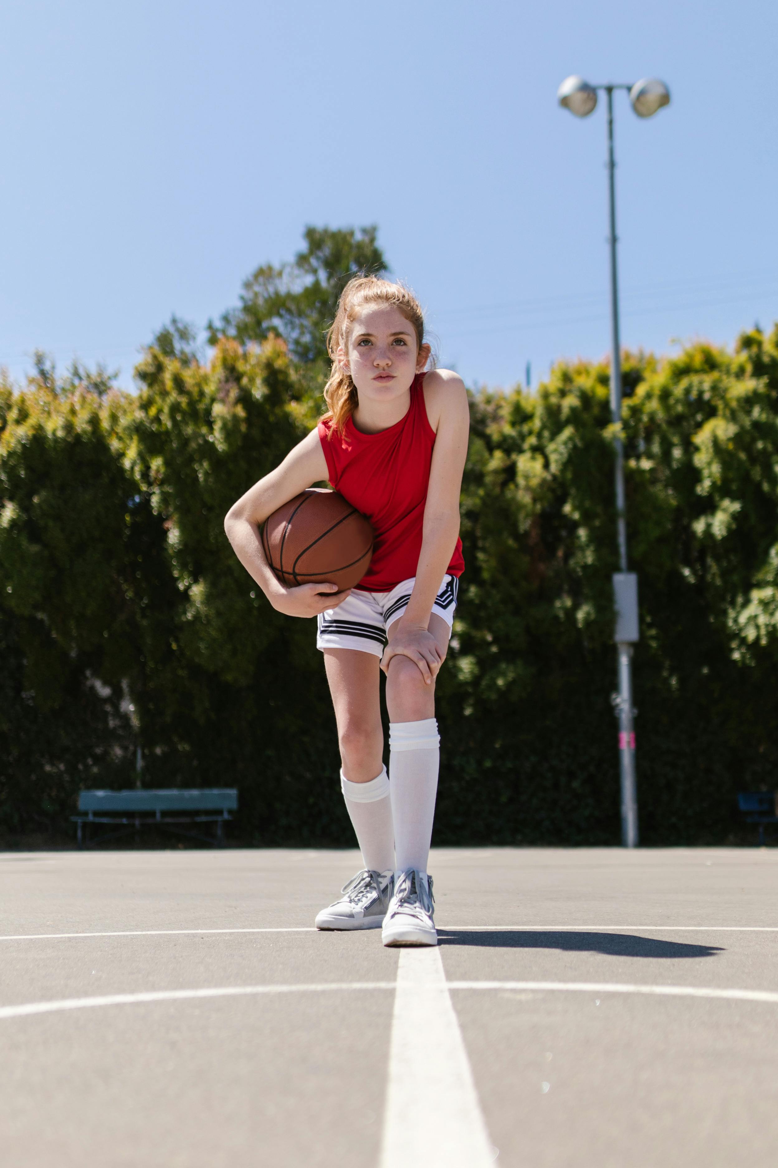 girl in red tank top holding a ball