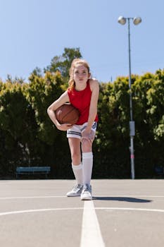 Dynamic shot of a young female basketball player posing confidently on an outdoor court.