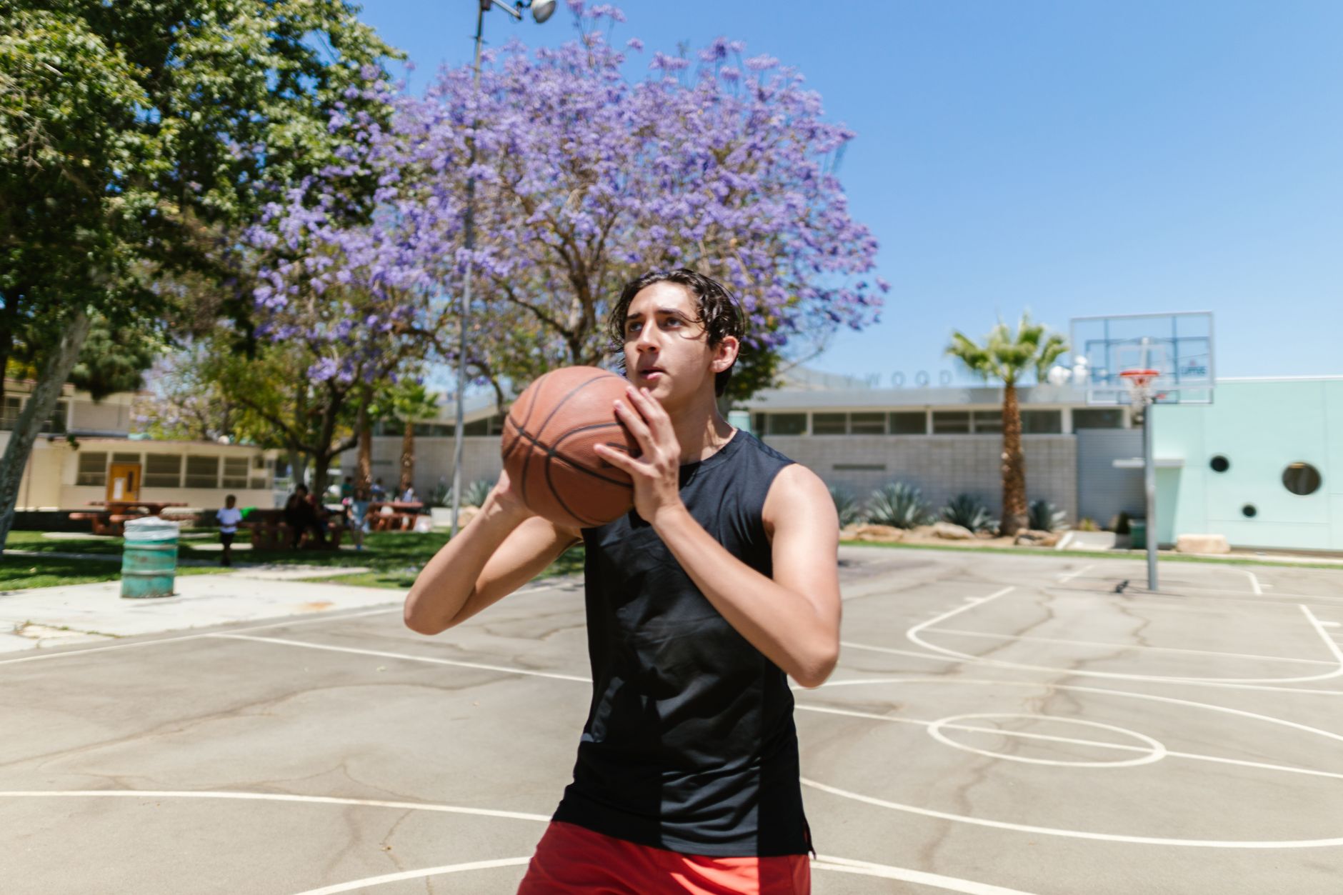 A young basketball guard practicing low dribbles alone on an outdoor court at sunset