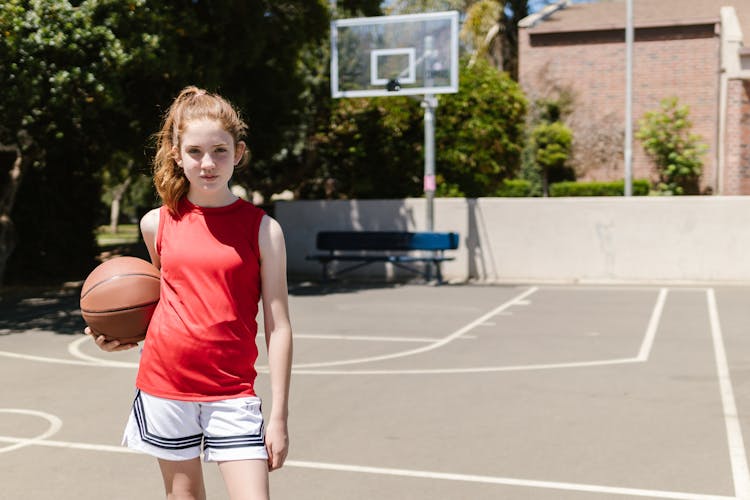 A Girl In A Tank Top Holding A Basketball