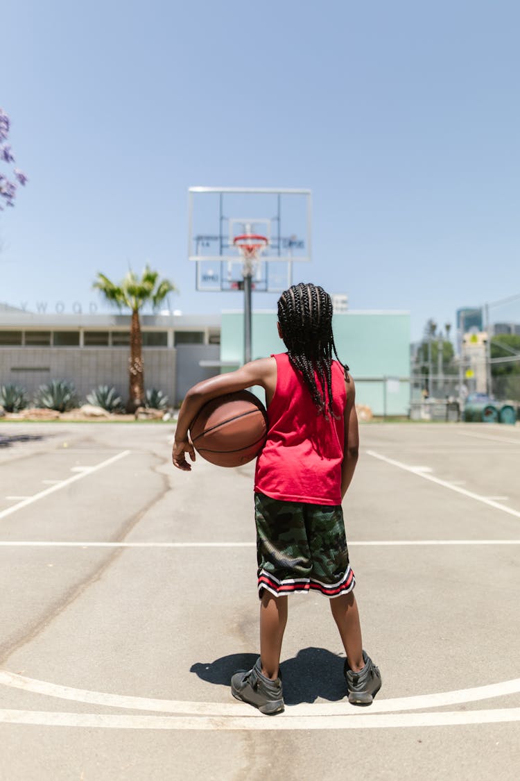 Boy In Red Jersey Standing On A Basketball Court