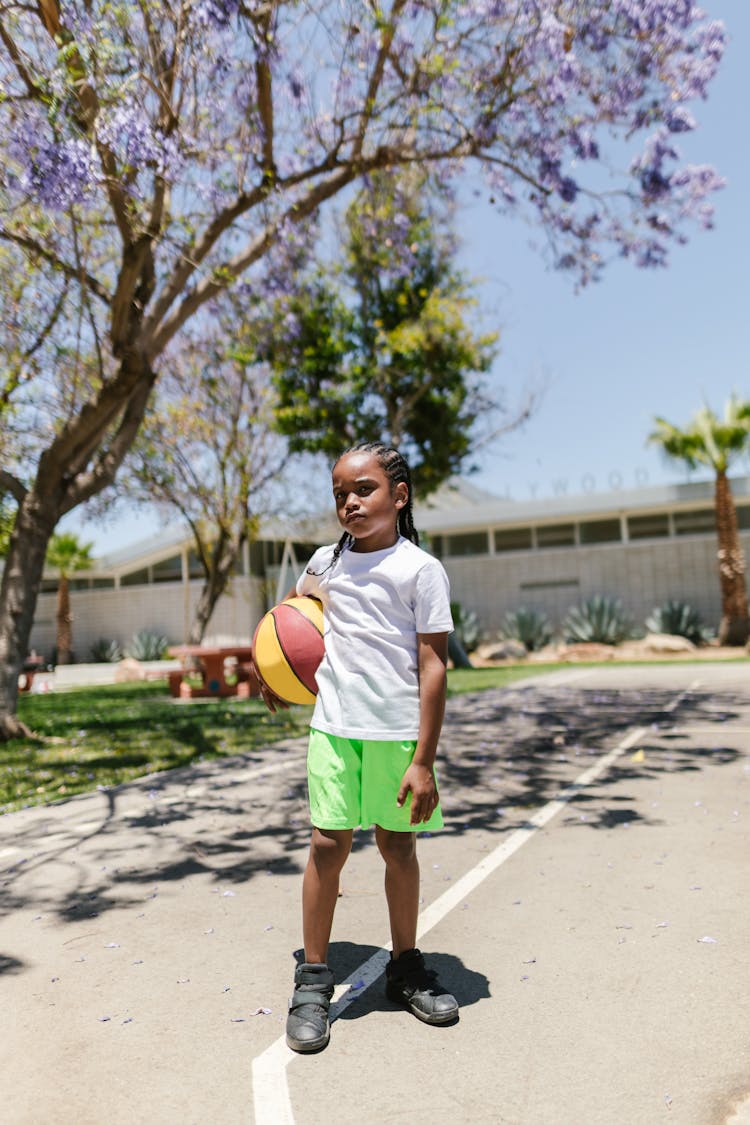 Girl In White Shirt And Green Shorts Holding A Basketball