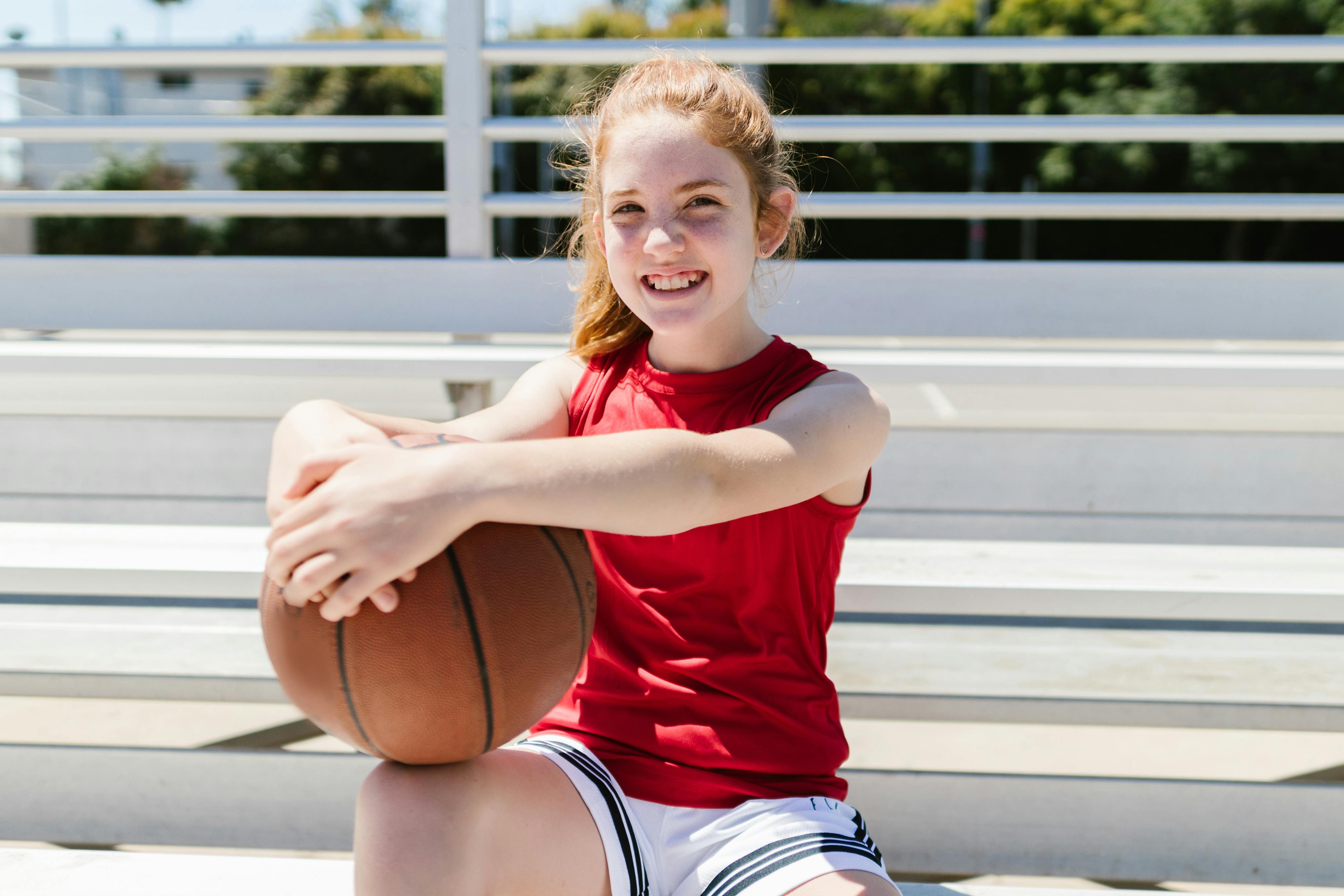 girl in red tank top holding a basketball