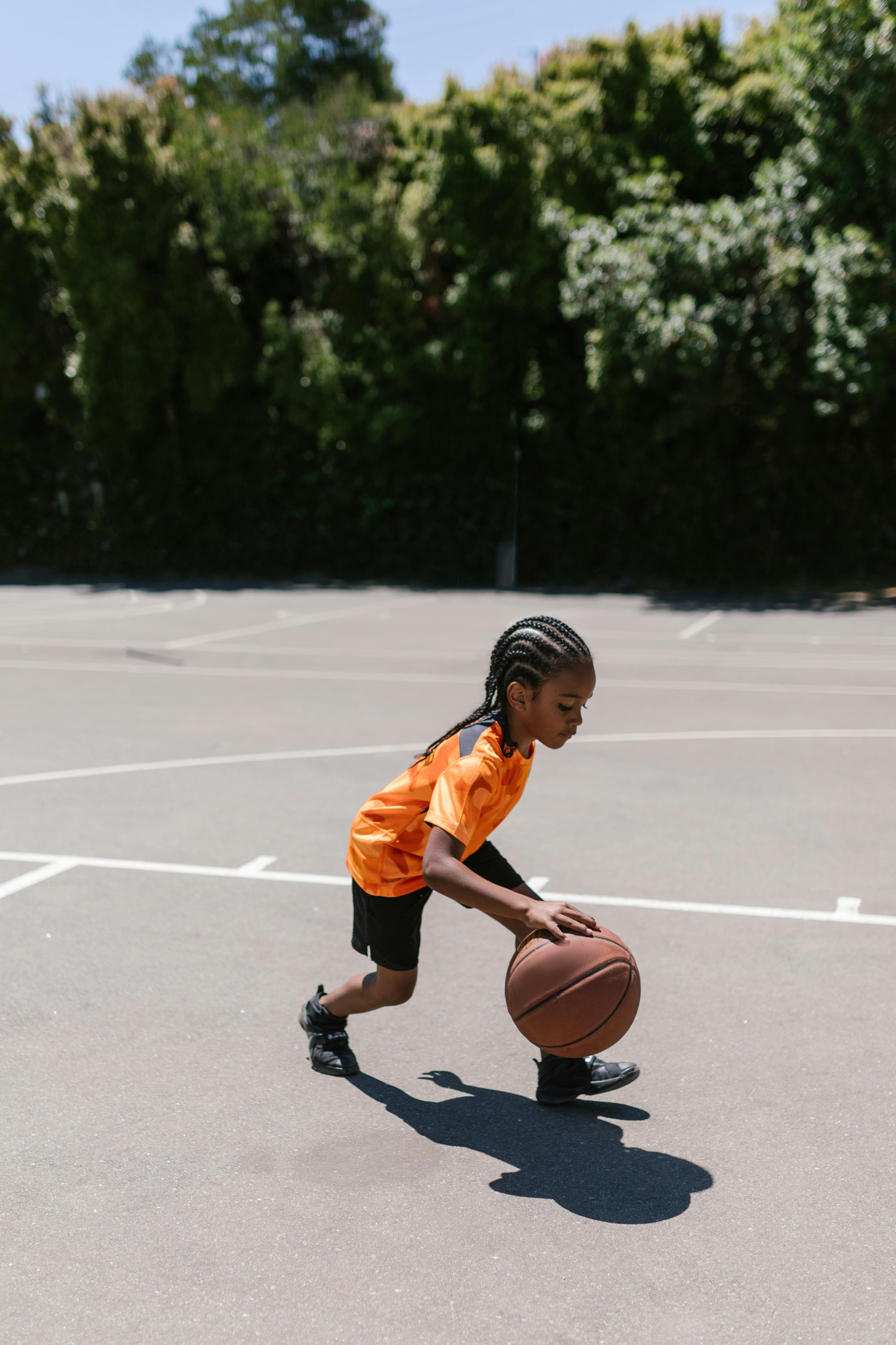 boy in orange jersey shirt playing basketball