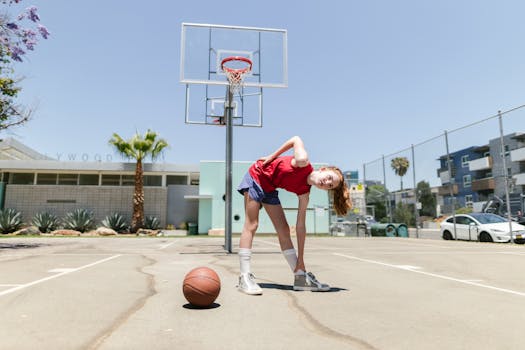 Teen girl bends and stretches during a workout on an outdoor basketball court.