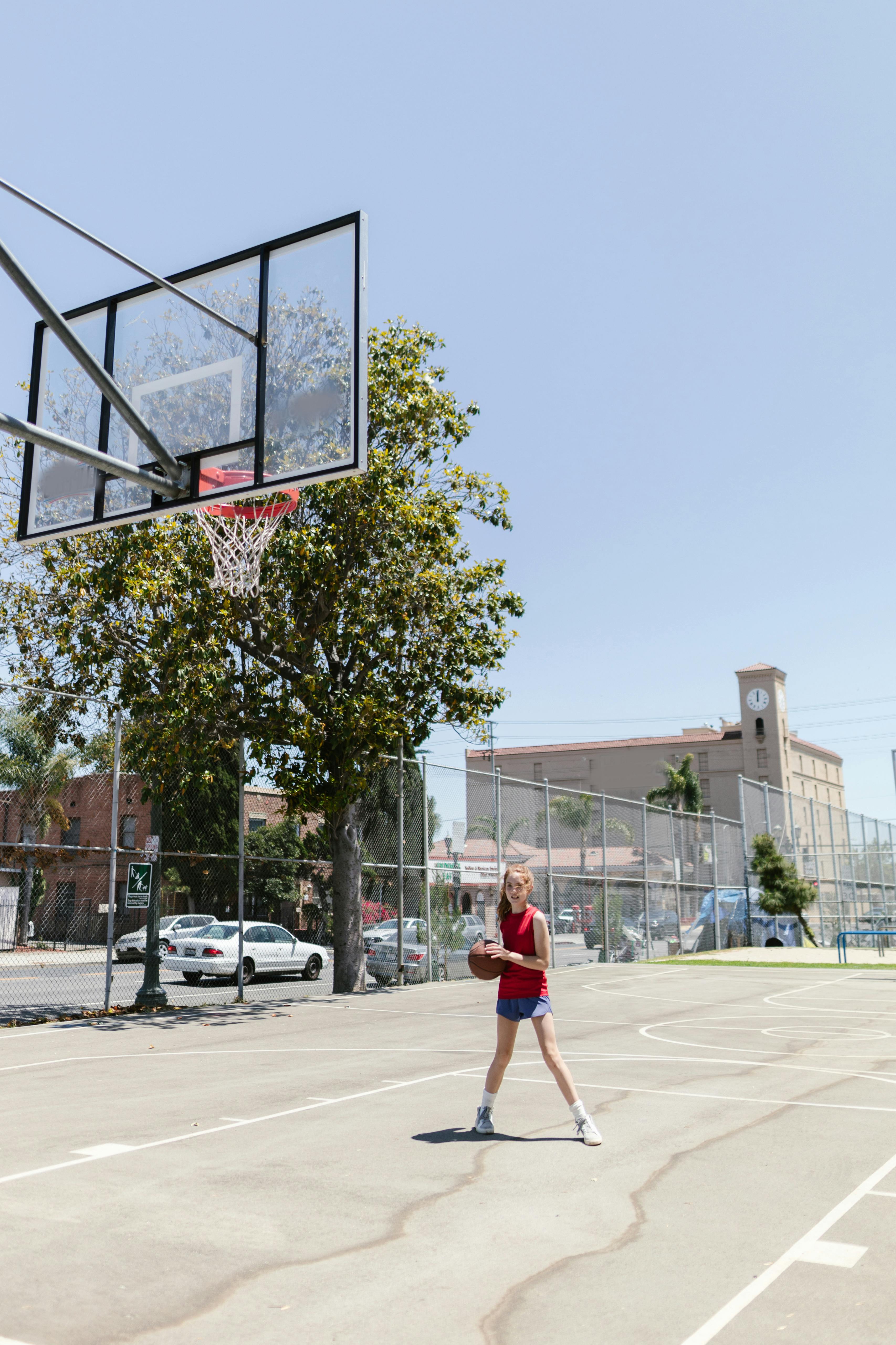 girl in red sleeveless shirt holding basketball