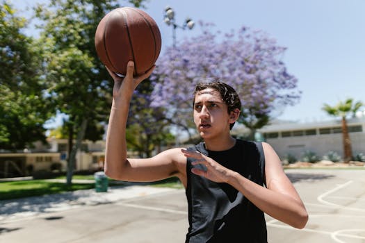Young male teenager playing basketball on an outdoor court, aiming for a shot.