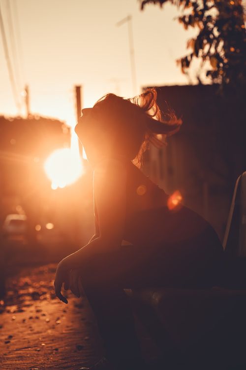 Free Captivating silhouette of a woman sitting on a bench during sunset, capturing a serene and reflective moment. Stock Photo