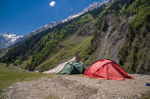 Free Picturesque campsite near Sonamarg, featuring vibrant tents against majestic mountain landscapes. Stock Photo