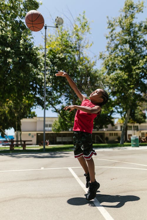 Boy in Black Shorts and Red Sleeveless Shirt Playing Basketball