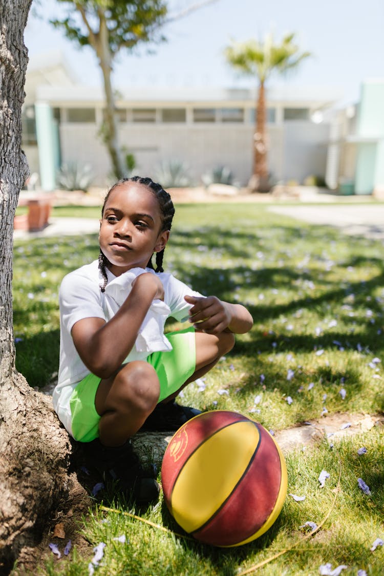 Little Boy Sitting Beside A Tree On A Park