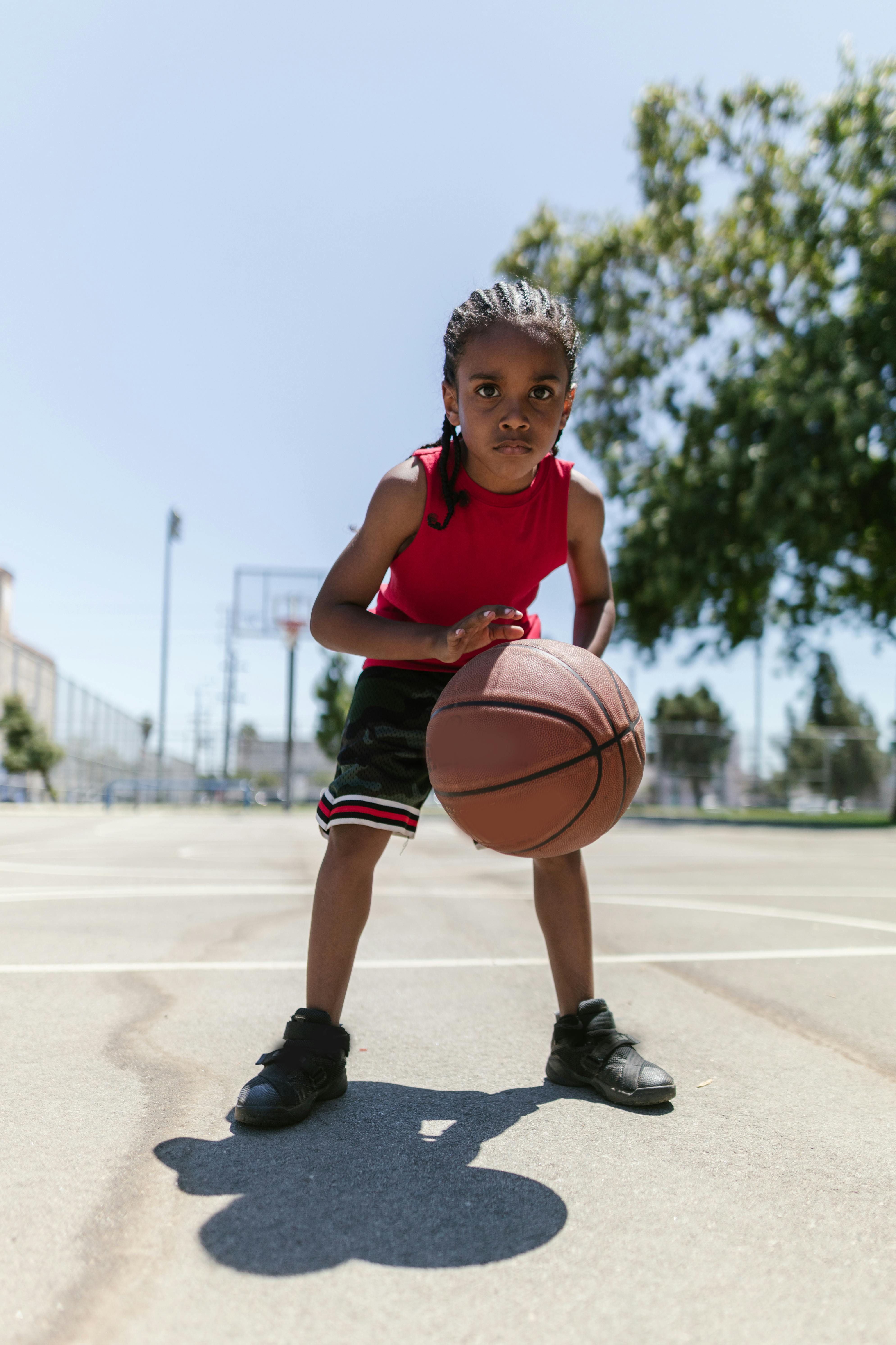 boy wearing a red jersey dribbling a ball