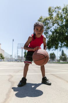 Energetic child playing basketball on a sunny outdoor court, showcasing determination.