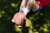 Person in White Socks and White Socks Holding Brown Basketball