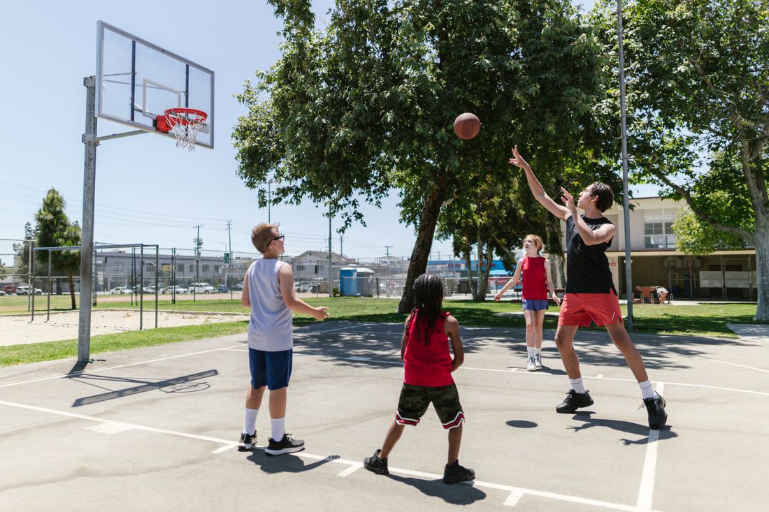 Young people playing basketball together on an outdoor community court