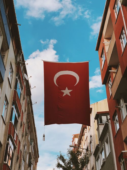 Free A Turkish flag hangs prominently between buildings under a bright blue sky in Sultangazi, Istanbul. Stock Photo