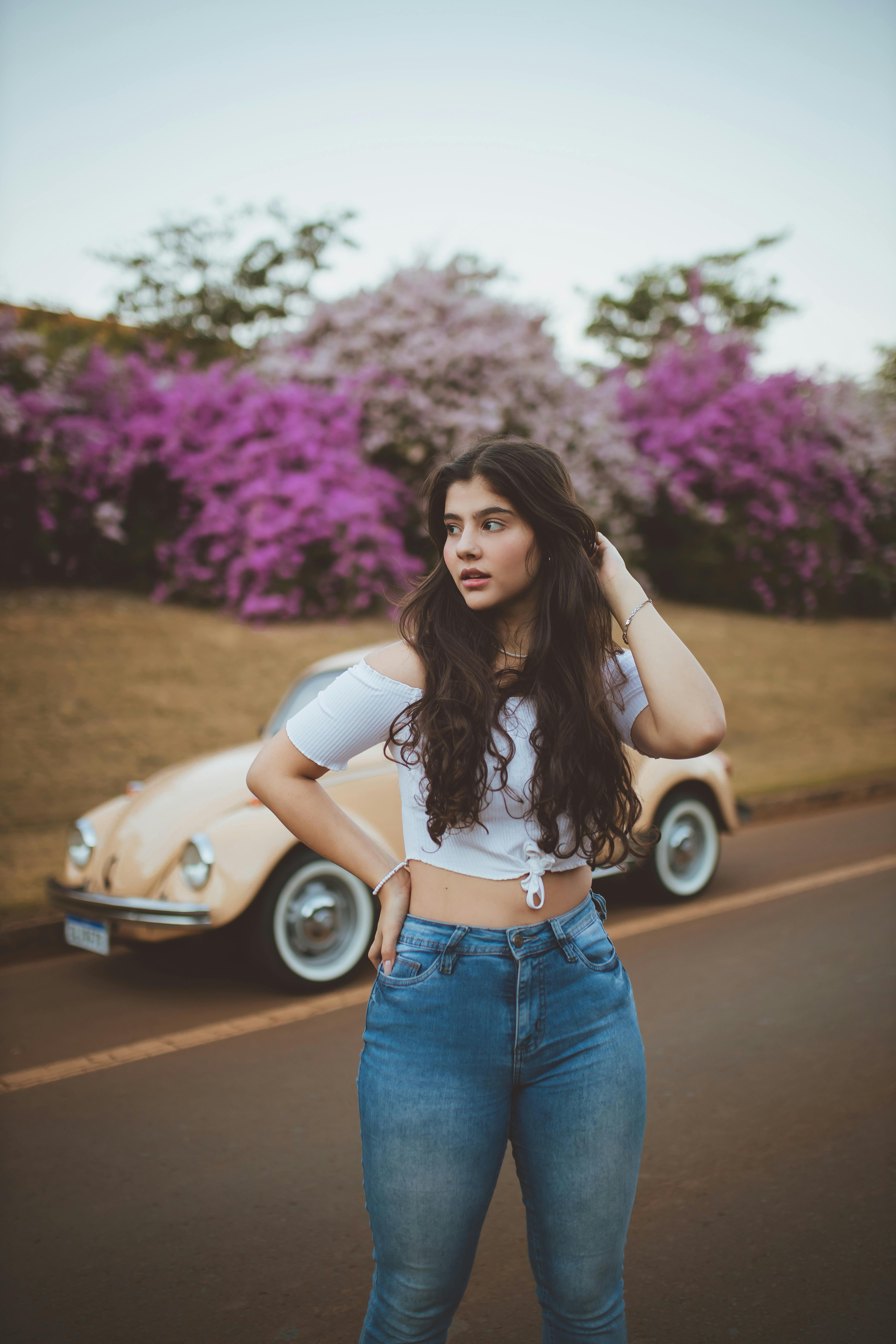 Woman in White Crop Top and Blue Denim Jeans Standing on Road · Free Stock  Photo