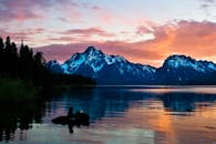 珍妮湖的日出令人叹为观止，白雪皑皑的山脉和宁静的水域映照着充满活力的天空