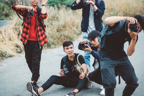 Free A group of young photographers capturing the outdoor scene with cameras in a natural setting. Stock Photo