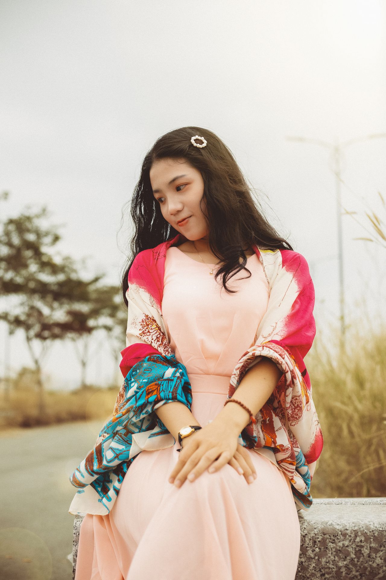 Woman in a pink dress with a colorful shawl draped over her shoulders