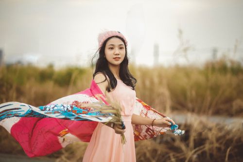 Free Young woman in a pink dress and beanie enjoying a windy day outdoors, smiling and carefree. Stock Photo