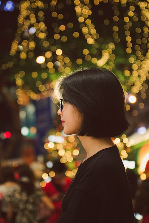 Woman in Black Shirt Standing Beside Christmas Lights