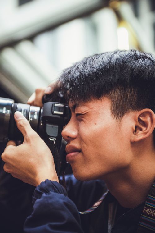Free Focused photographer using DSLR camera indoors, capturing an intimate moment. Stock Photo