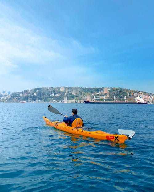 A Back View of a Person Riding a Kayak on Sea
