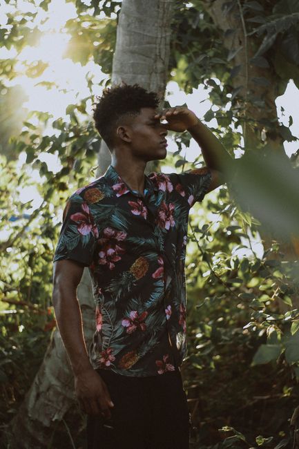 A young man in floral shirt enjoys the sunlight in a lush Brazilian forest.
