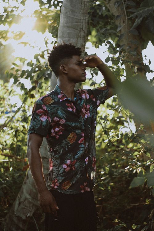 Free A young man in floral shirt enjoys the sunlight in a lush Brazilian forest. Stock Photo