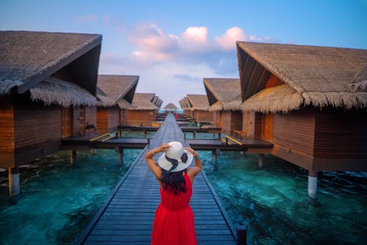 A woman in a red dress explores overwater bungalows in the Maldives, showcasing a tropical vacation setting.