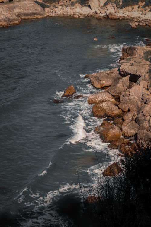 Free A picturesque rocky coast with ocean waves gently crashing onto the shore. Stock Photo