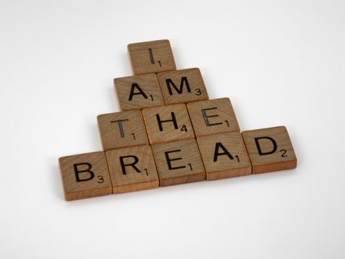 Free Scrabble tiles arranged to spell 'I Am The Bread' on a white background. Stock Photo