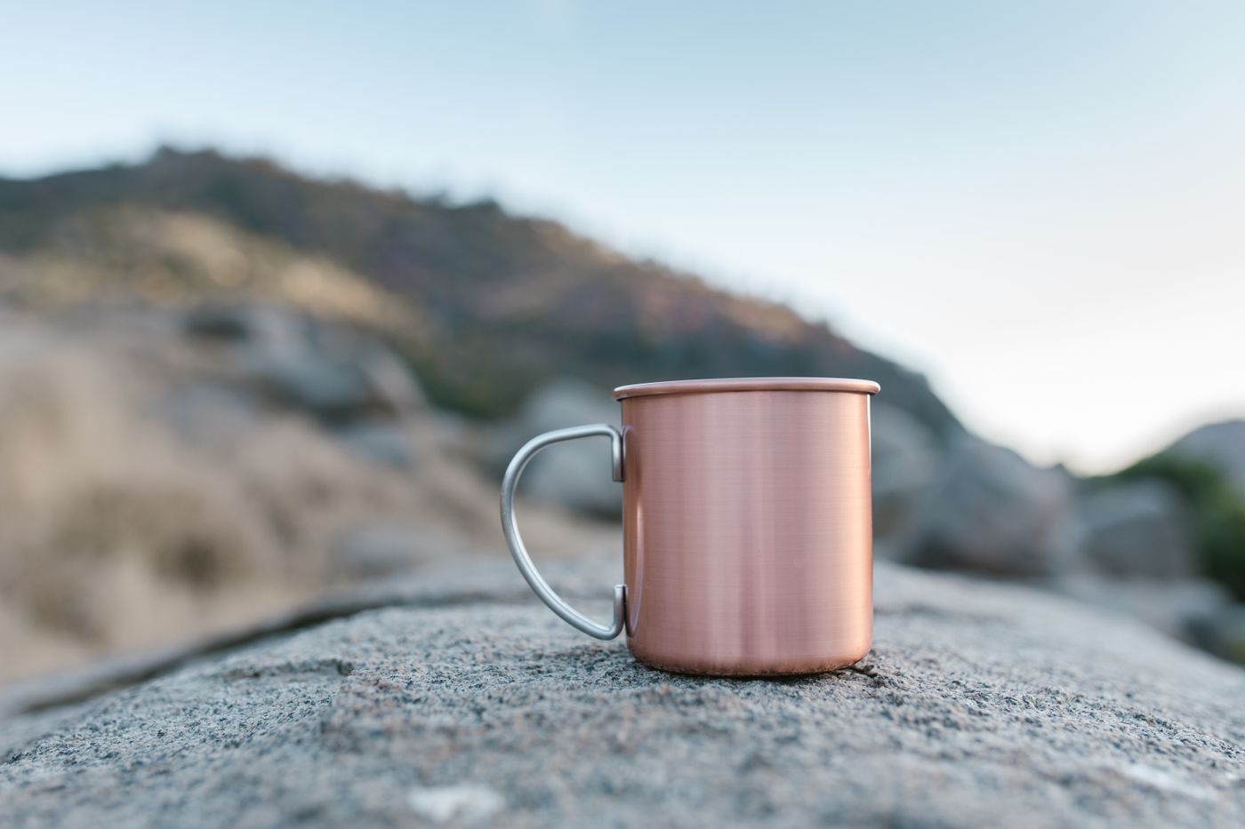 Copper engraved tumbler on a rock outdoors