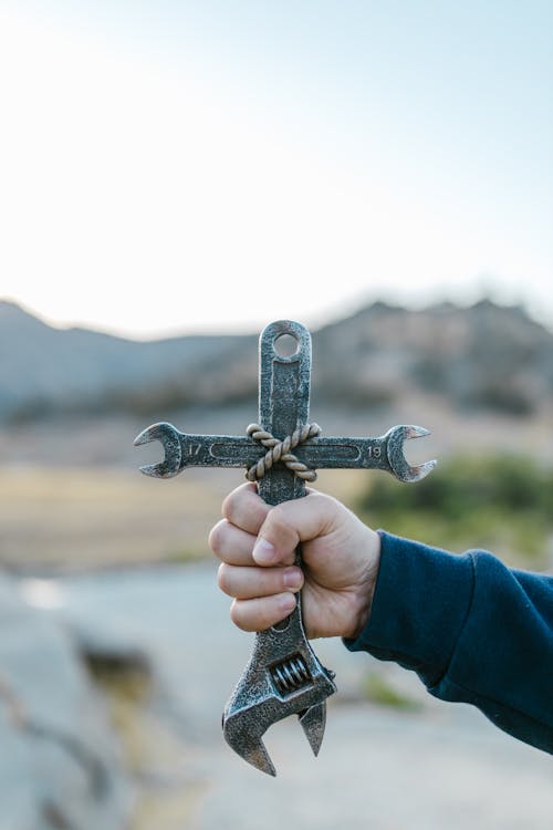 A Person Holding A Crucifix Made of Tools