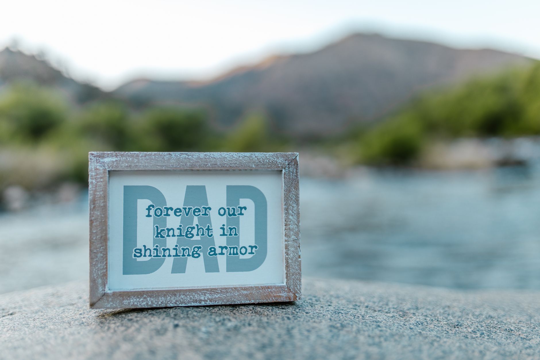 Close-up of a framed Father's Day message by a serene riverside, perfect for celebrations.