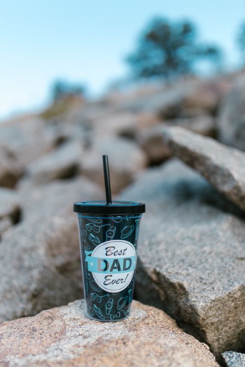 Free Blue tumbler with Best Dad Ever text placed on rocks outdoors. Stock Photo